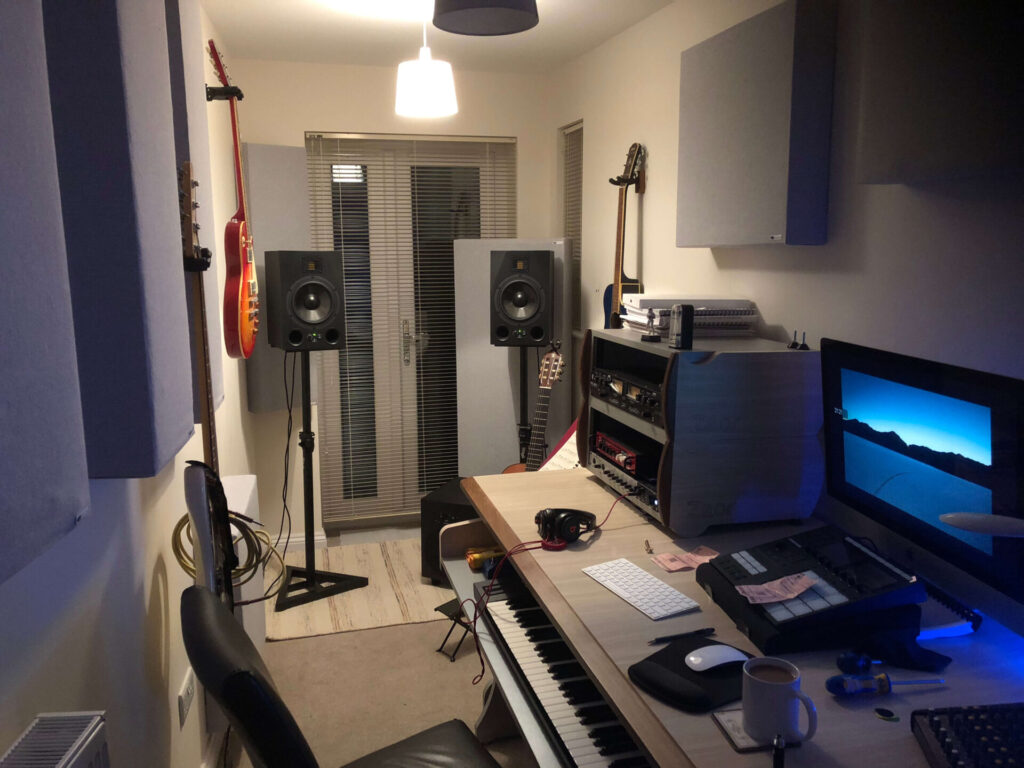 music-studio-with-guitars-hanging-on-wall-a-desk-and-speakers